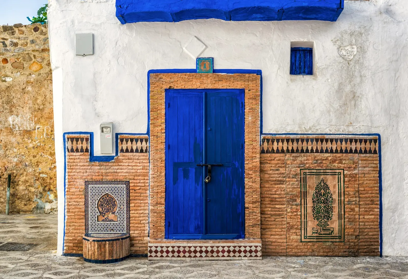 Porte bleue et zellige sur une façade blanche de la médina d’Asilah