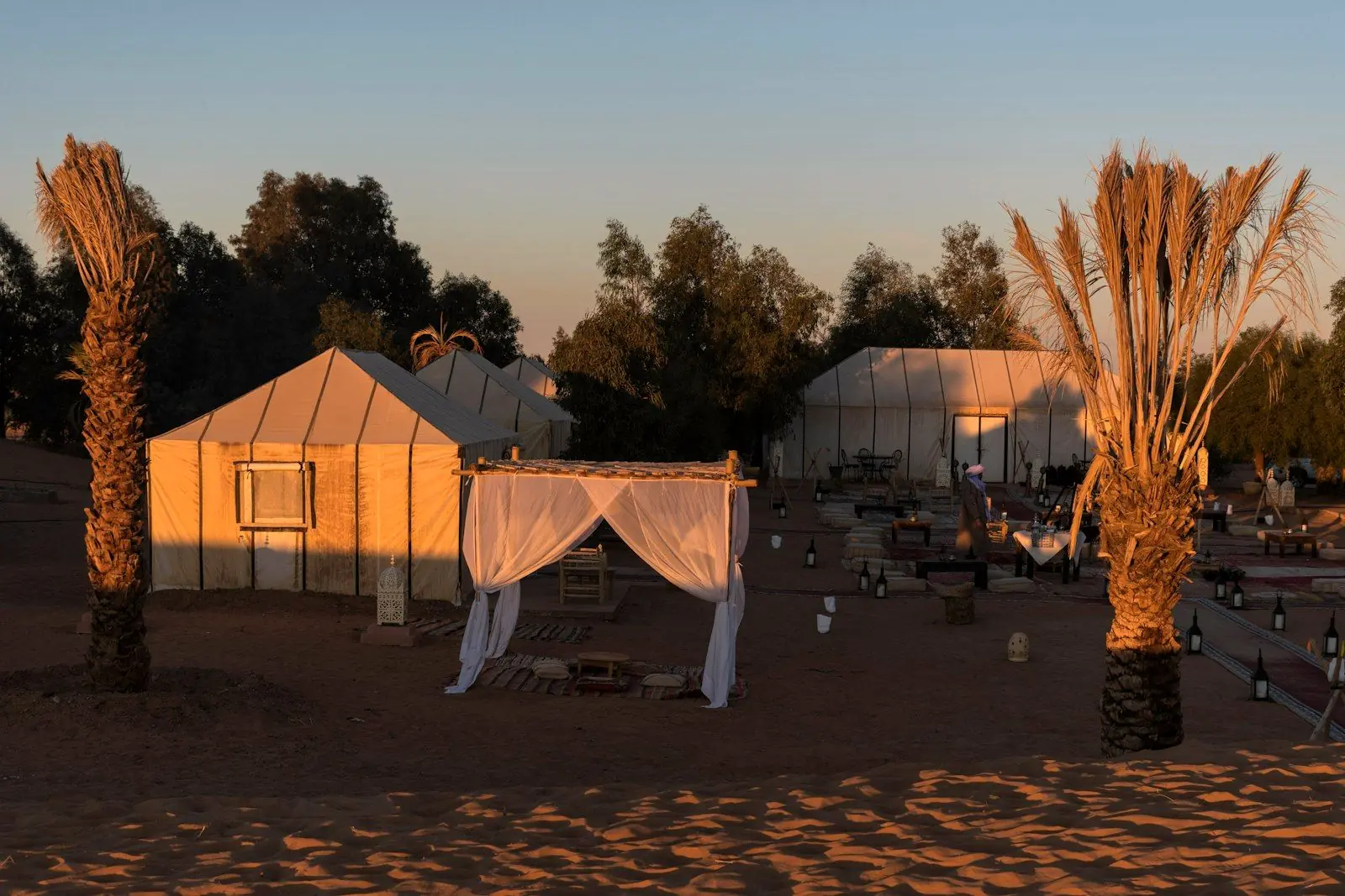 Camp dans le désert à l’heure dorée, tentes et lanternes