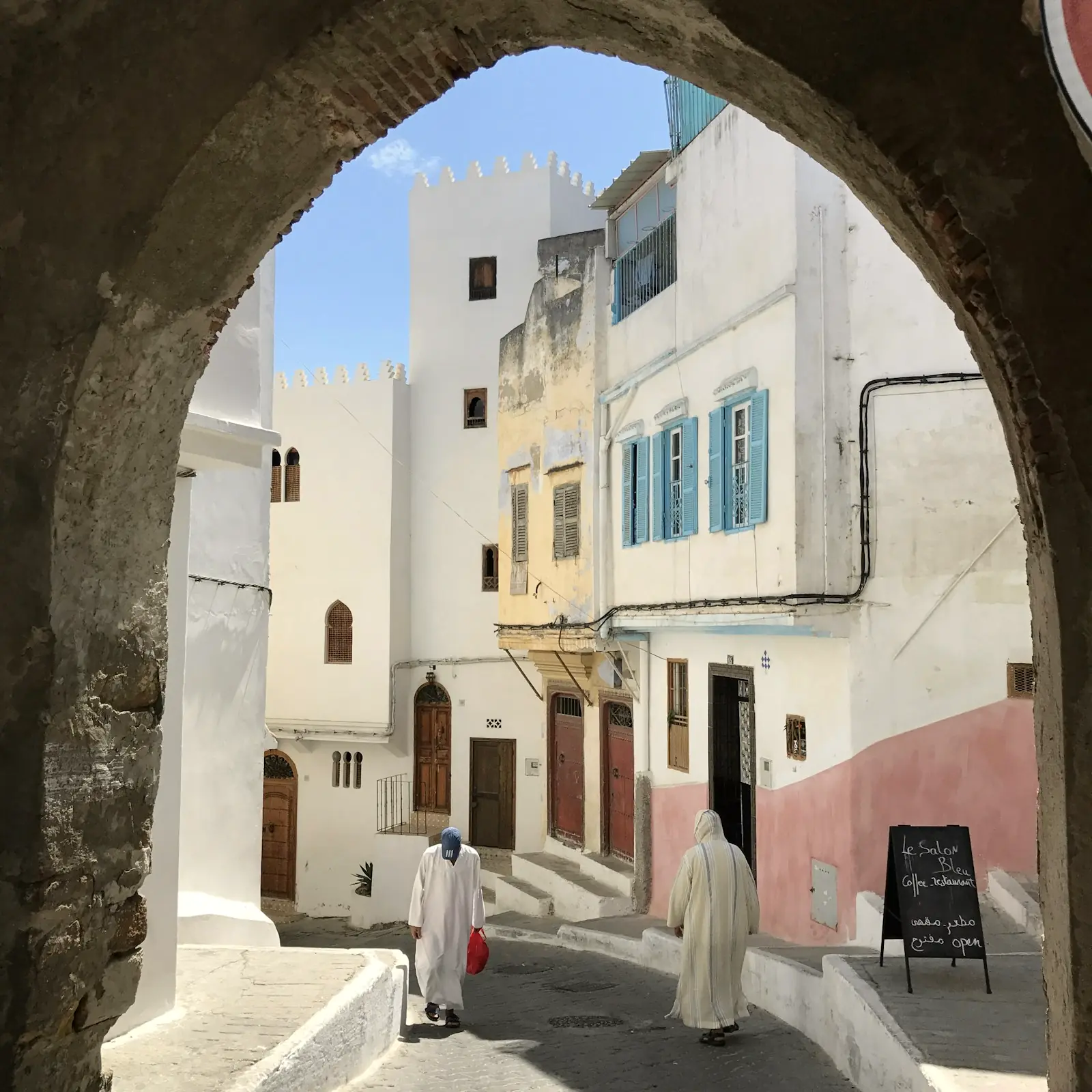 Ruelle blanche de la kasbah de Tanger vue à travers une arche