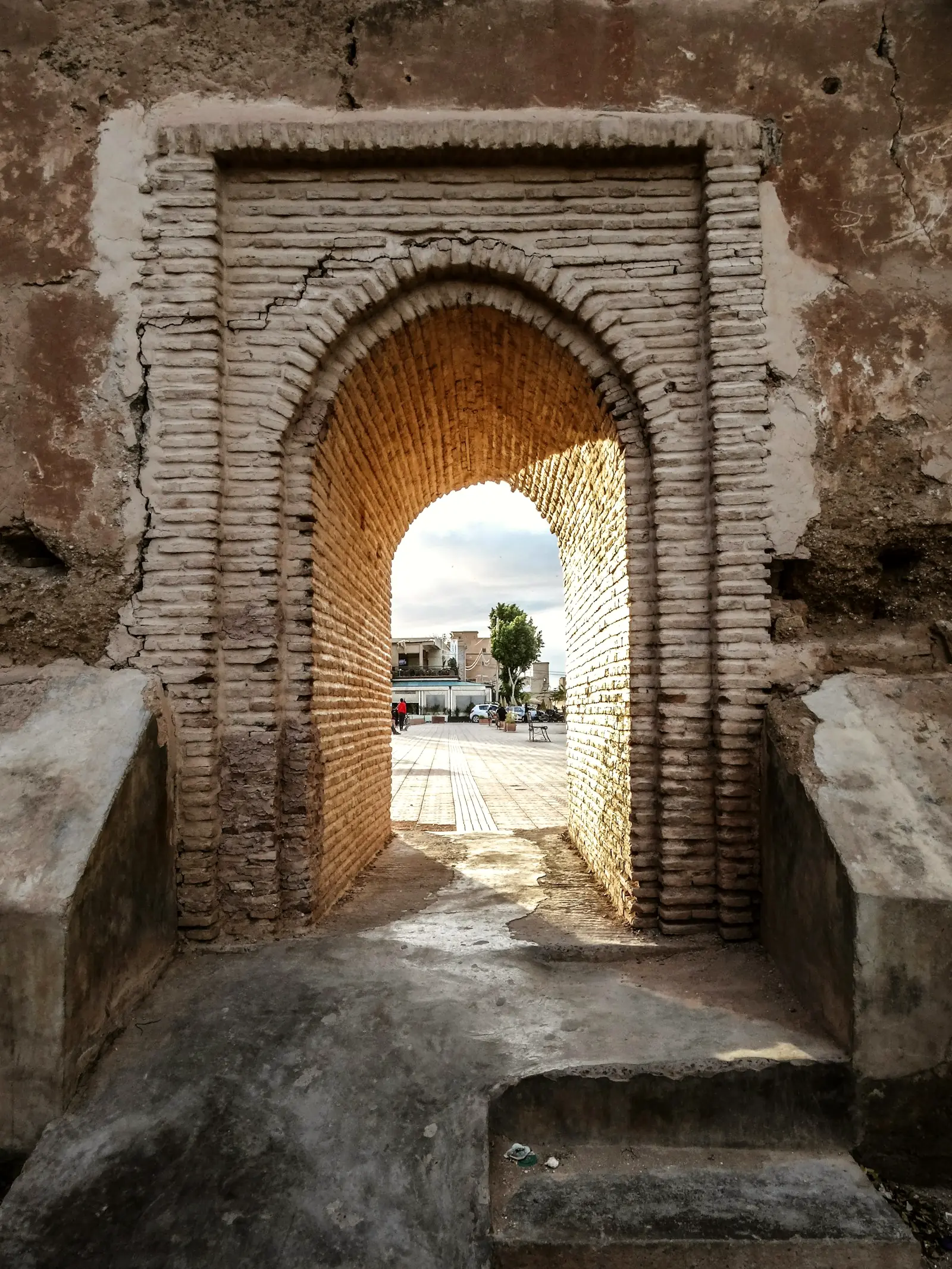 Porte de pisé en arc brisé ouvrant sur une place de Taroudant