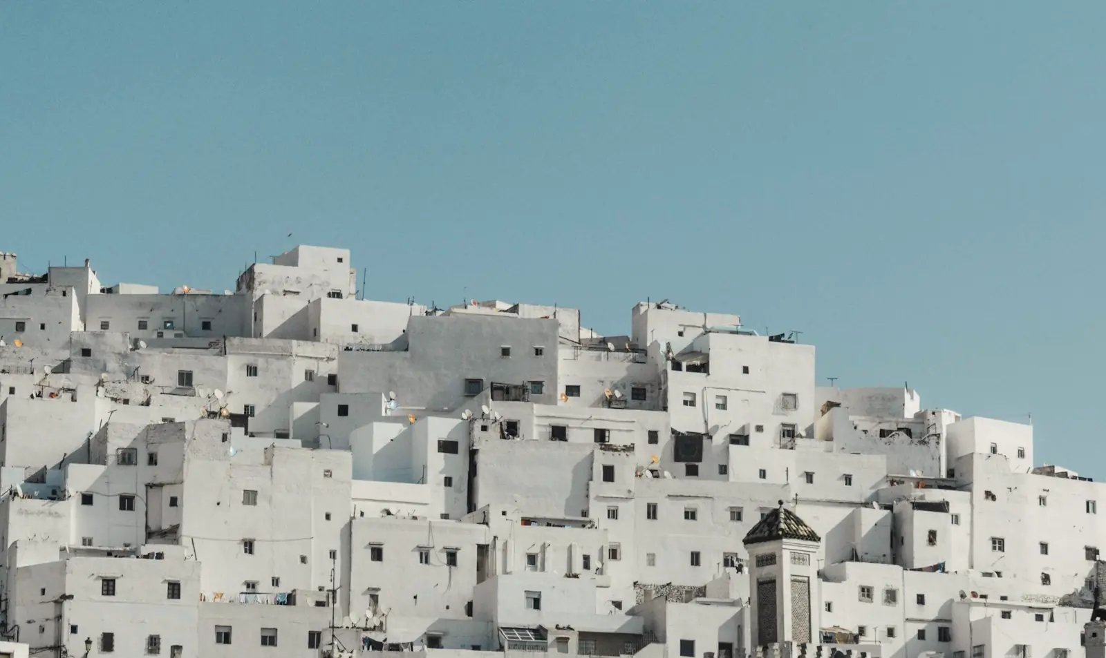 Maisons blanches étagées sur une colline, sous un ciel bleu