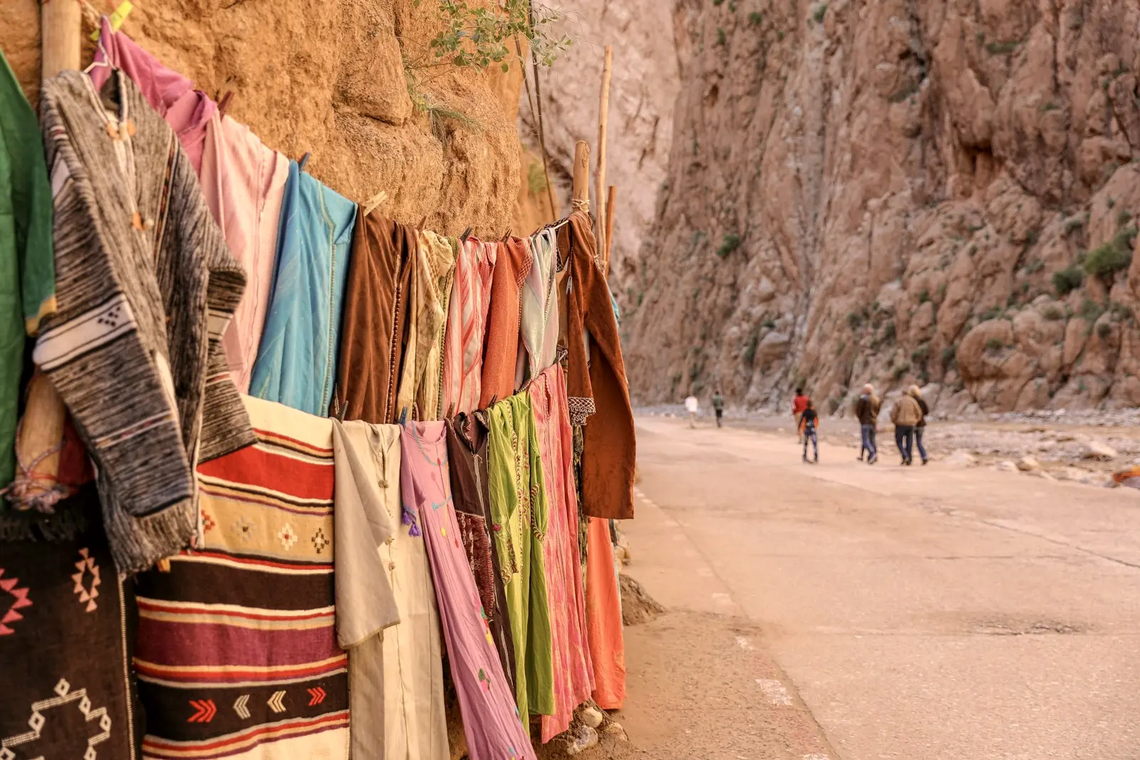 Tapis et tissus colorés suspendus au pied des falaises des gorges du Todra